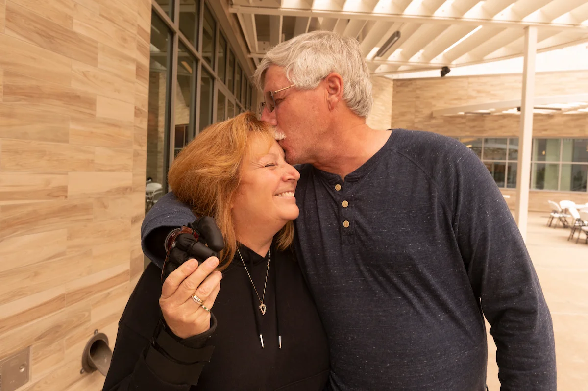 David Brockman kisses the top of his wife, Tereasa Brockman's forehead 