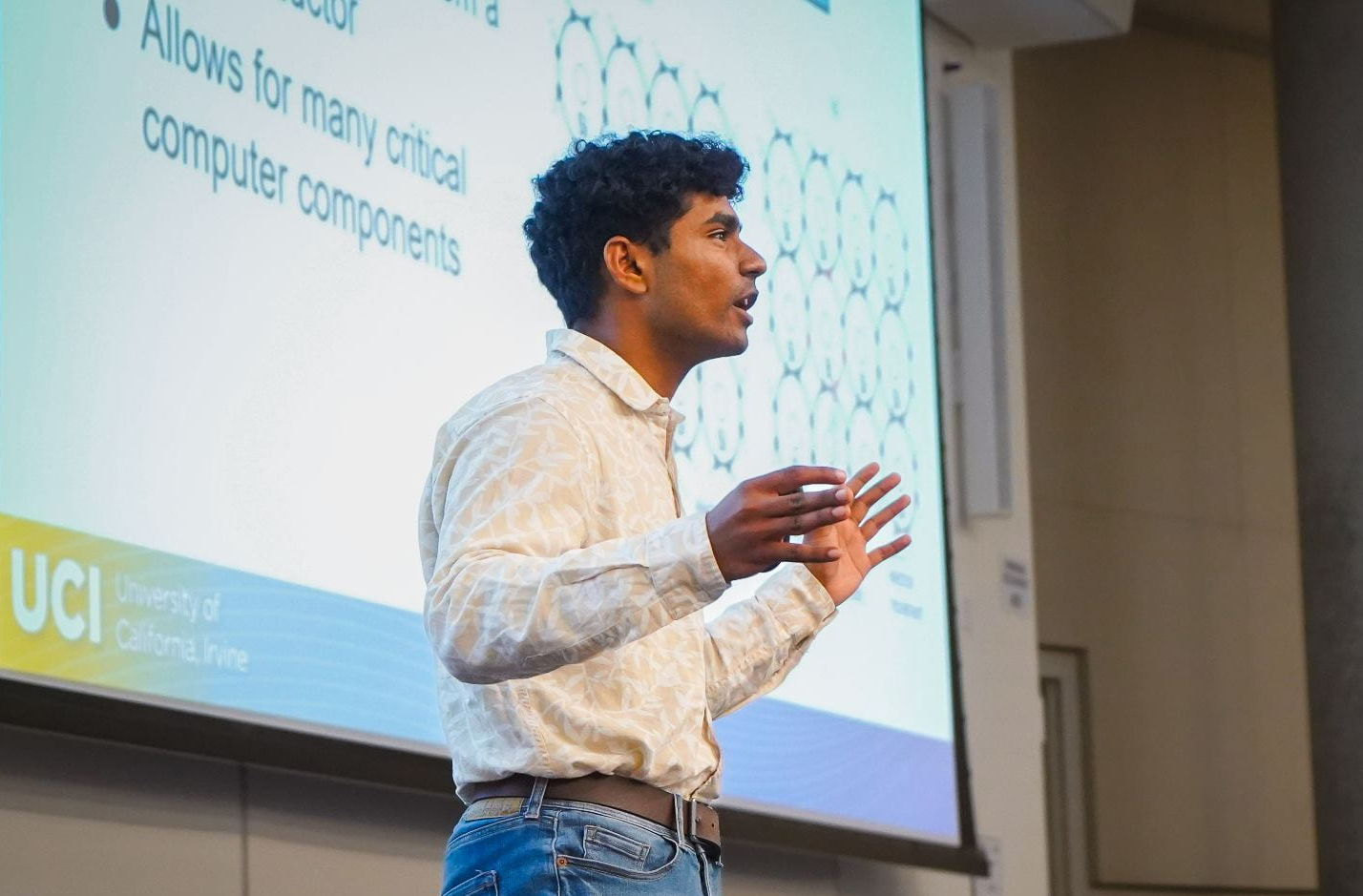 Kaustubh Simha talks to unseen crowd in front of a powerpoint slide.
