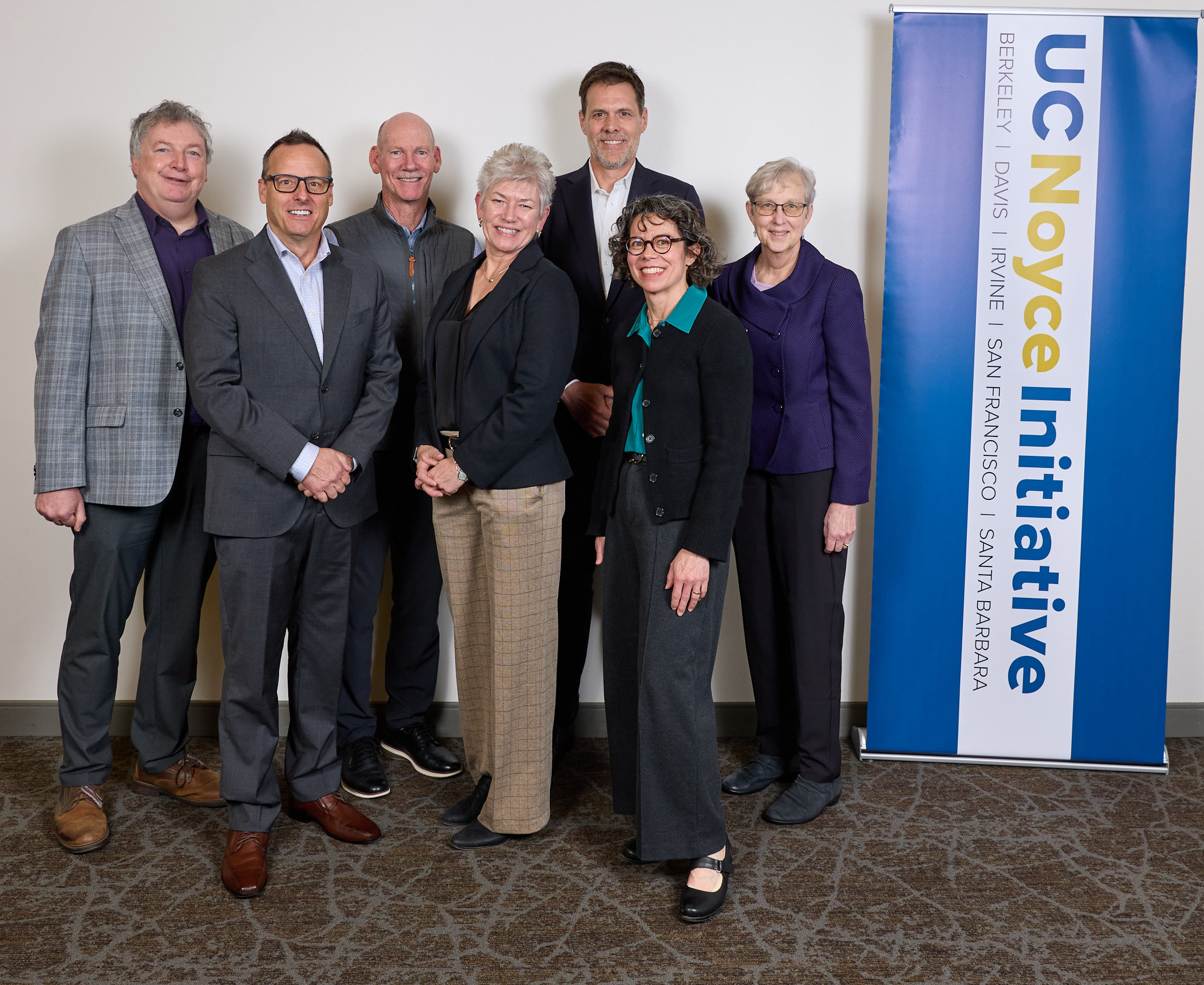 Five vice chancellors of research stand in group with member of Robert Noyce trust by UC Noyce Initiative banner.