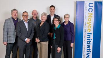 Five vice chancellors of research stand in group with member of Robert Noyce trust by UC Noyce Initiative banner.