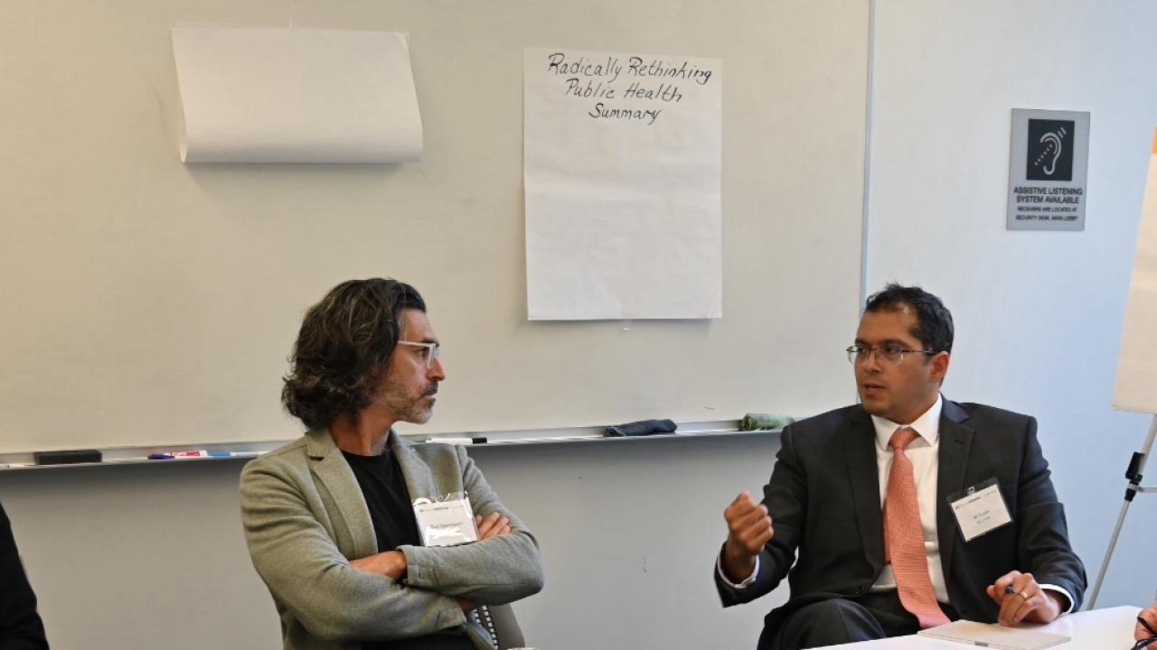 Four people sit around a board room engaged in coversation.