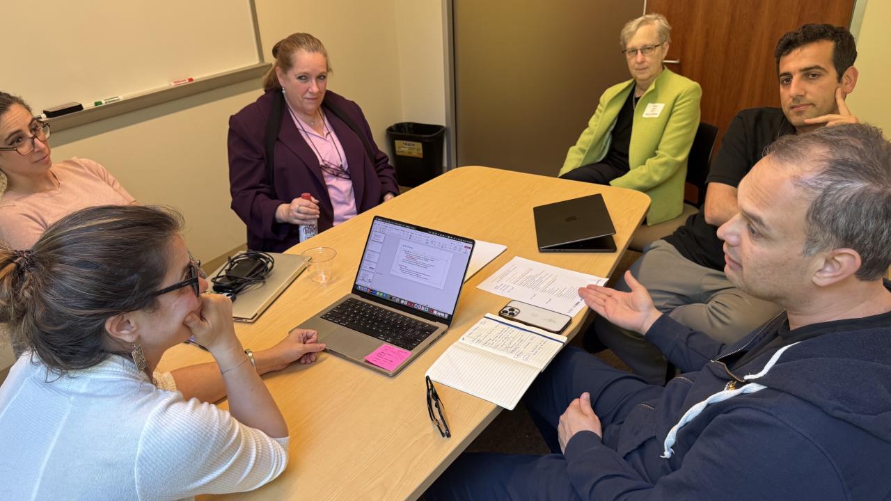 four women and two men around a table engaged in conversation