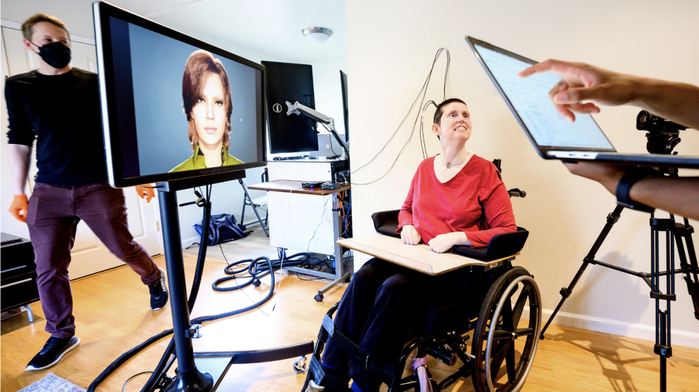 Ann, a research participant in a study of speech neuroprostheses led by UCSF's Edward Chang, is connected to computers that translate her brain signals into the speech and facial movements of an avatar. At left is UCSF clinical research coordinator Max Dougherty. (Photo by Noah Berger)