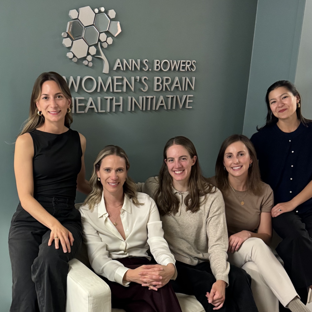 five women sit on a white couch with sign behind them that says Ann S Bowers Womens Brain Health Initiative