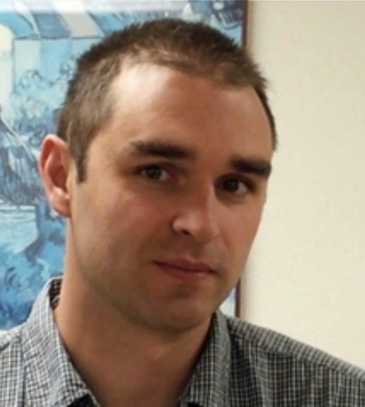 white man with buzzed haircut looks intently at camera.