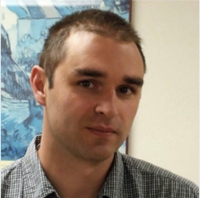 white man with buzzed haircut looks intently at camera.