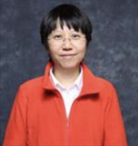Portrait of Sook Wah Yee. She is an Asian woman, has short hair, glasses and is wearing a bright orange coat.
