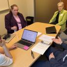 four women and two men around a table engaged in conversation